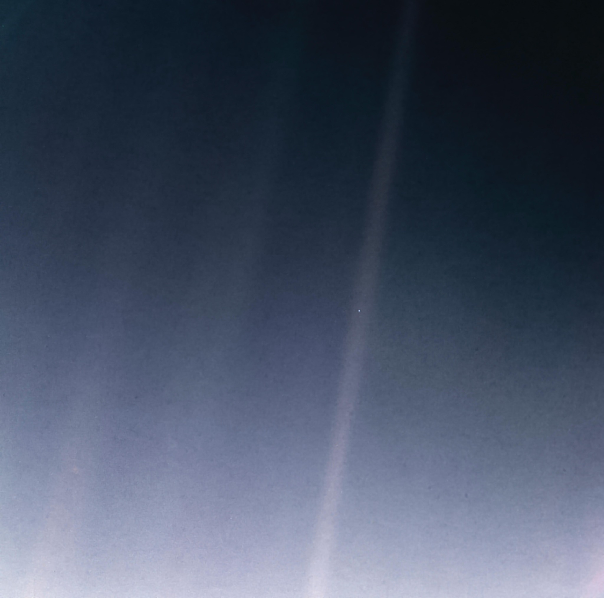 Earth photographed as a pale blue dot in a ray of sunlight
